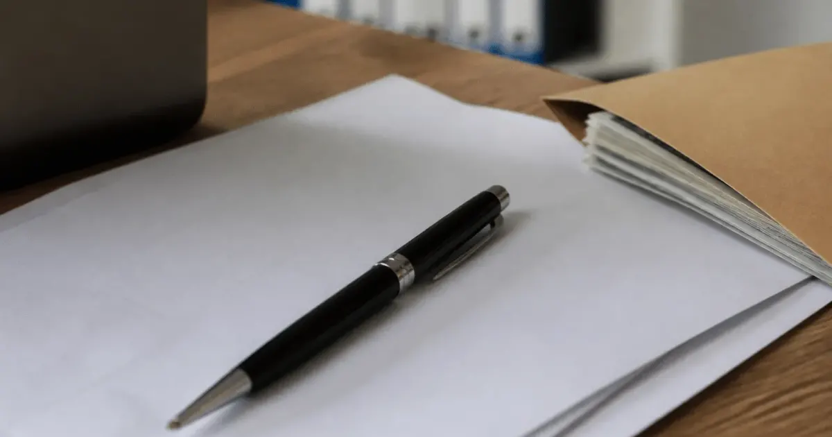 Stylo posé sur contrat immobilier avec enveloppe argent