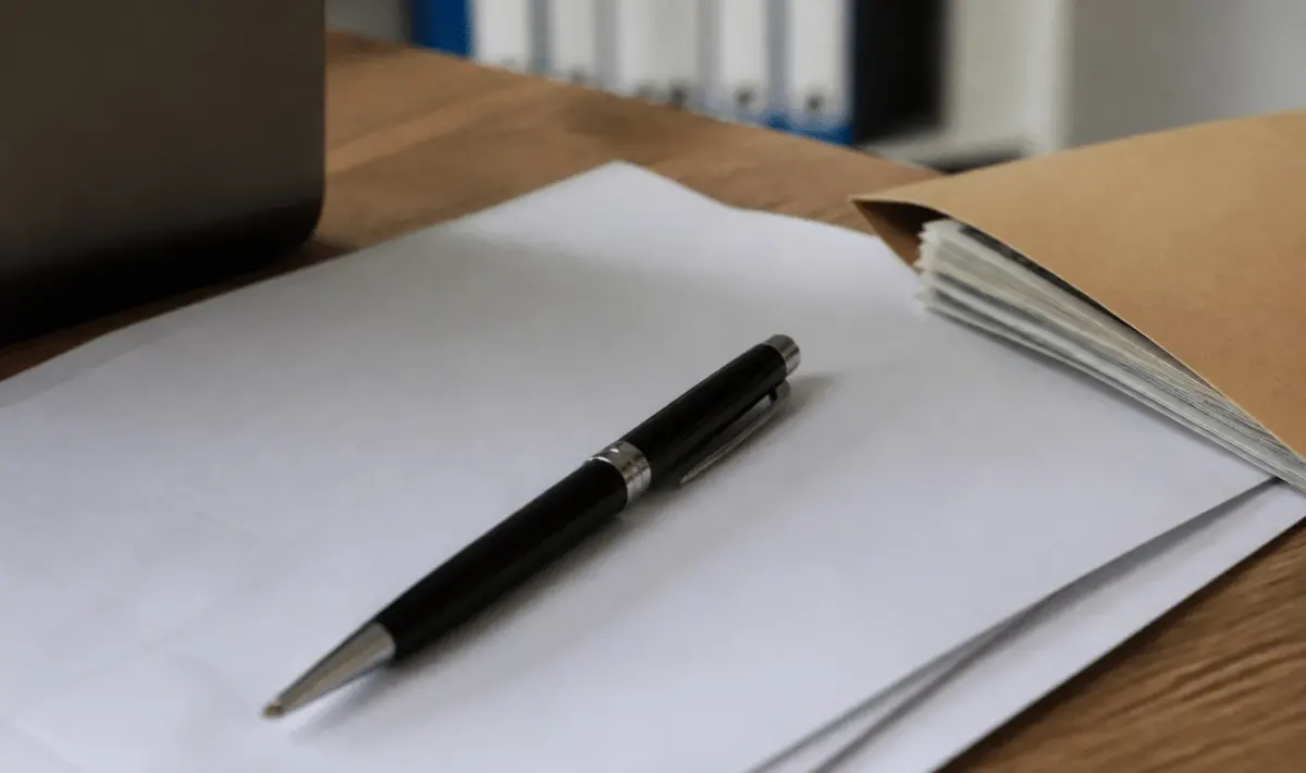 Stylo posé sur contrat immobilier avec enveloppe argent