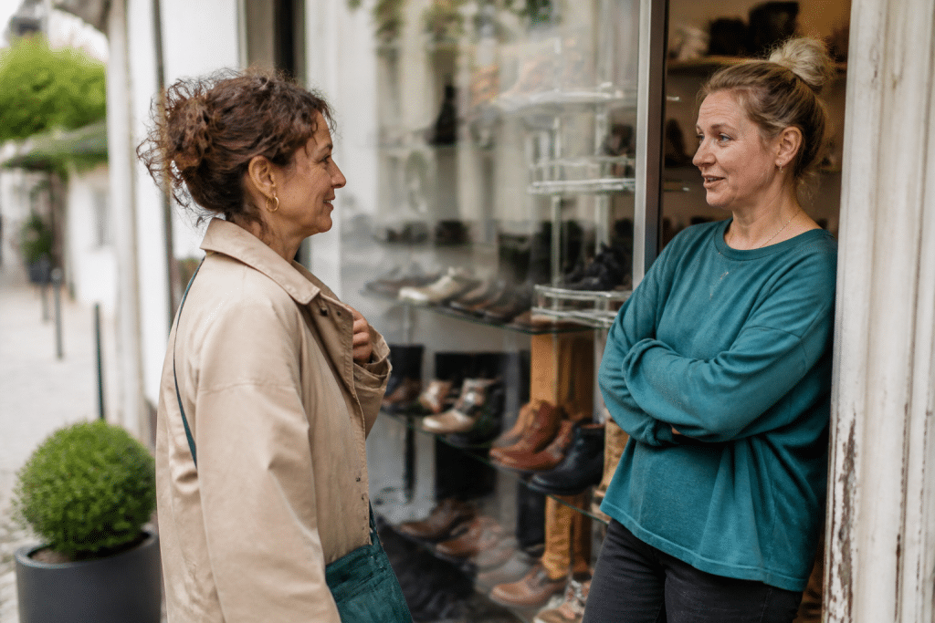 Personne discutant avec commercant devant vitrine quartier