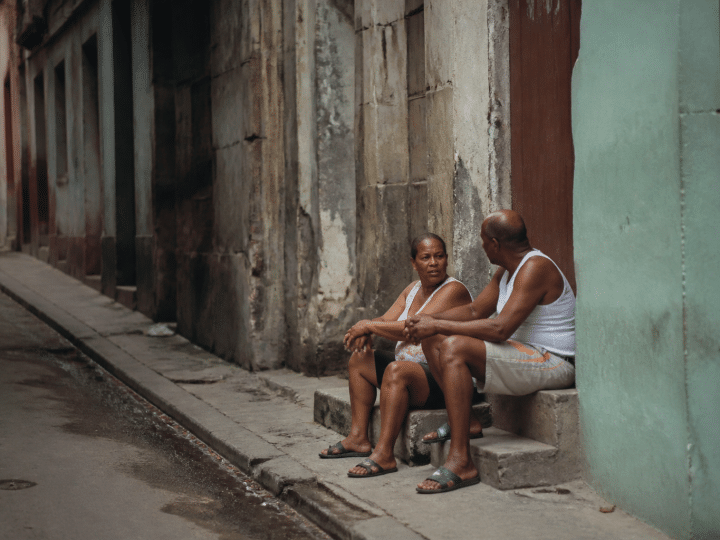 Rue sombre avec immeubles deteriores et habitants assis sur marches