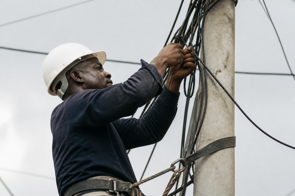 Technicien installant câbles électriques sur poteau réseau