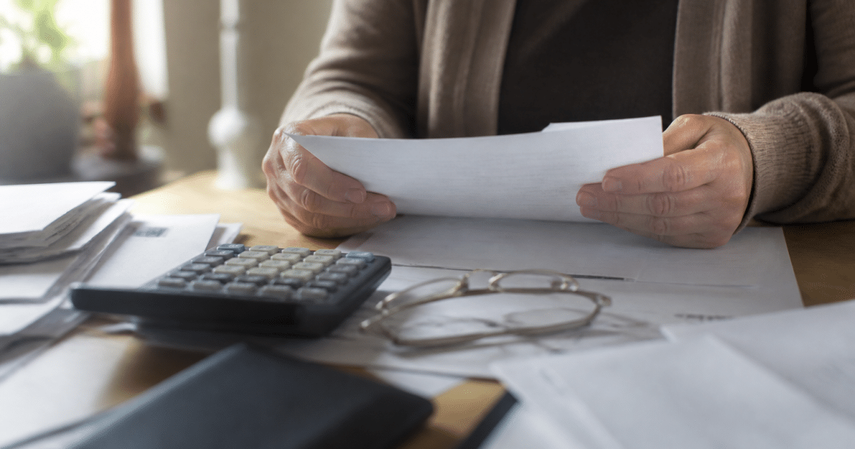 Personne tenant documents hypothecaires sur bureau avec calculatrice