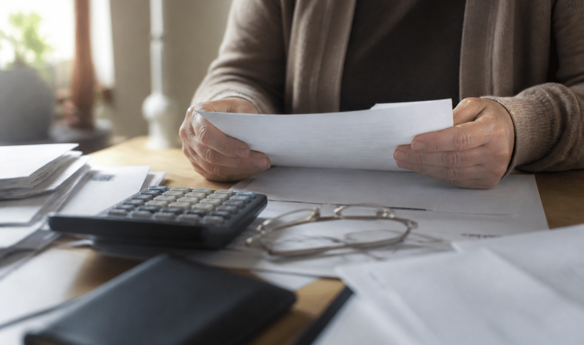 Personne tenant documents hypothecaires sur bureau avec calculatrice