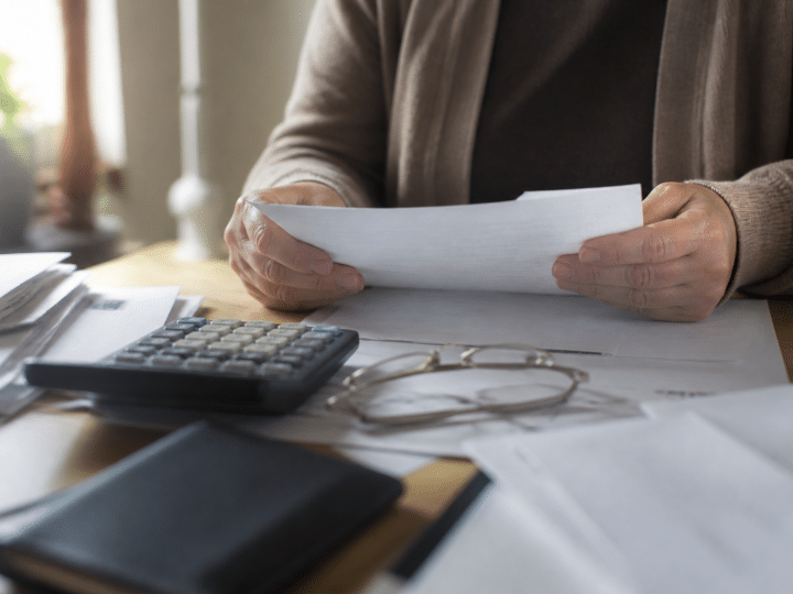 Personne tenant documents hypothecaires sur bureau avec calculatrice